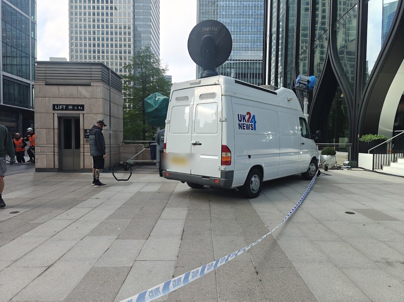 Rear three-quarter view of the UK24 News van with satellite dish raised against the towers of Canary Wharf